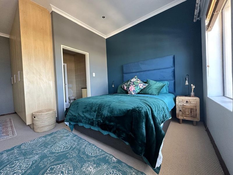 A well-maintained bedroom featuring built-in cupboards, a feature wall, and direct access to an en-suite bathroom.