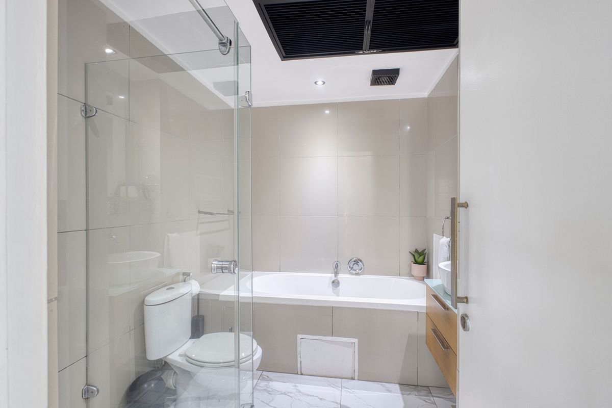 Modern bathroom featuring a glass-enclosed shower, a built-in bathtub, a wall-mounted vanity, and contemporary tiled finishes.