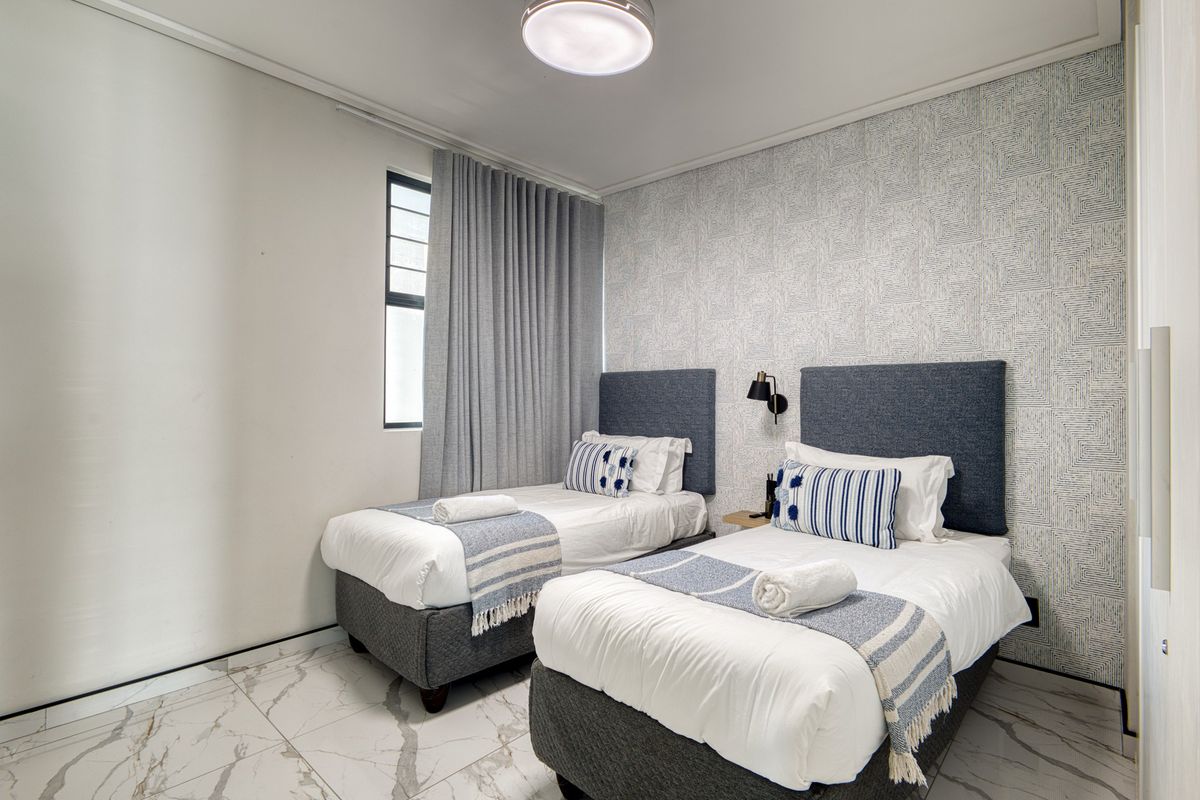 A well-maintained bedroom featuring marble-look floor tiles, textured accent wallpaper, and modern wall-mounted lighting.