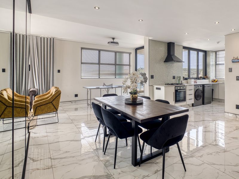 Modern open-plan living and dining area featuring high-end marble-look flooring, recessed lighting, and a sleek, well-equipped kitchen with integrated appliances.