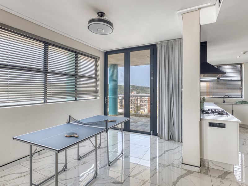 Modern open-plan living area featuring high-end marble-look floor tiles, a sleek kitchen with gas hob, and seamless access to a private balcony.