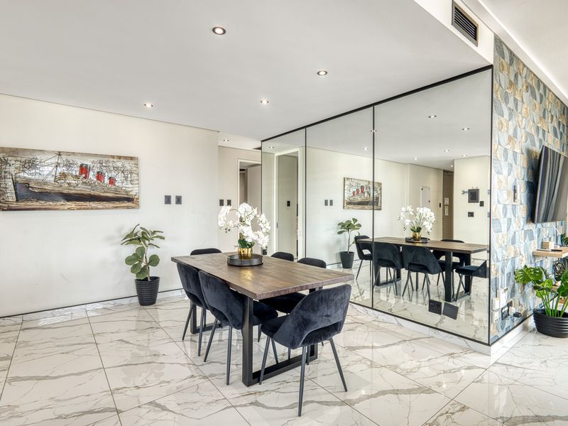 Modern dining area featuring polished marble-look floor tiles, recessed downlighting, and a large feature mirrored wall.