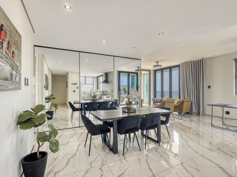 Spacious open-plan living and dining area featuring high-end marble-look floor tiles, modern recessed lighting, and seamless access to a private balcony.