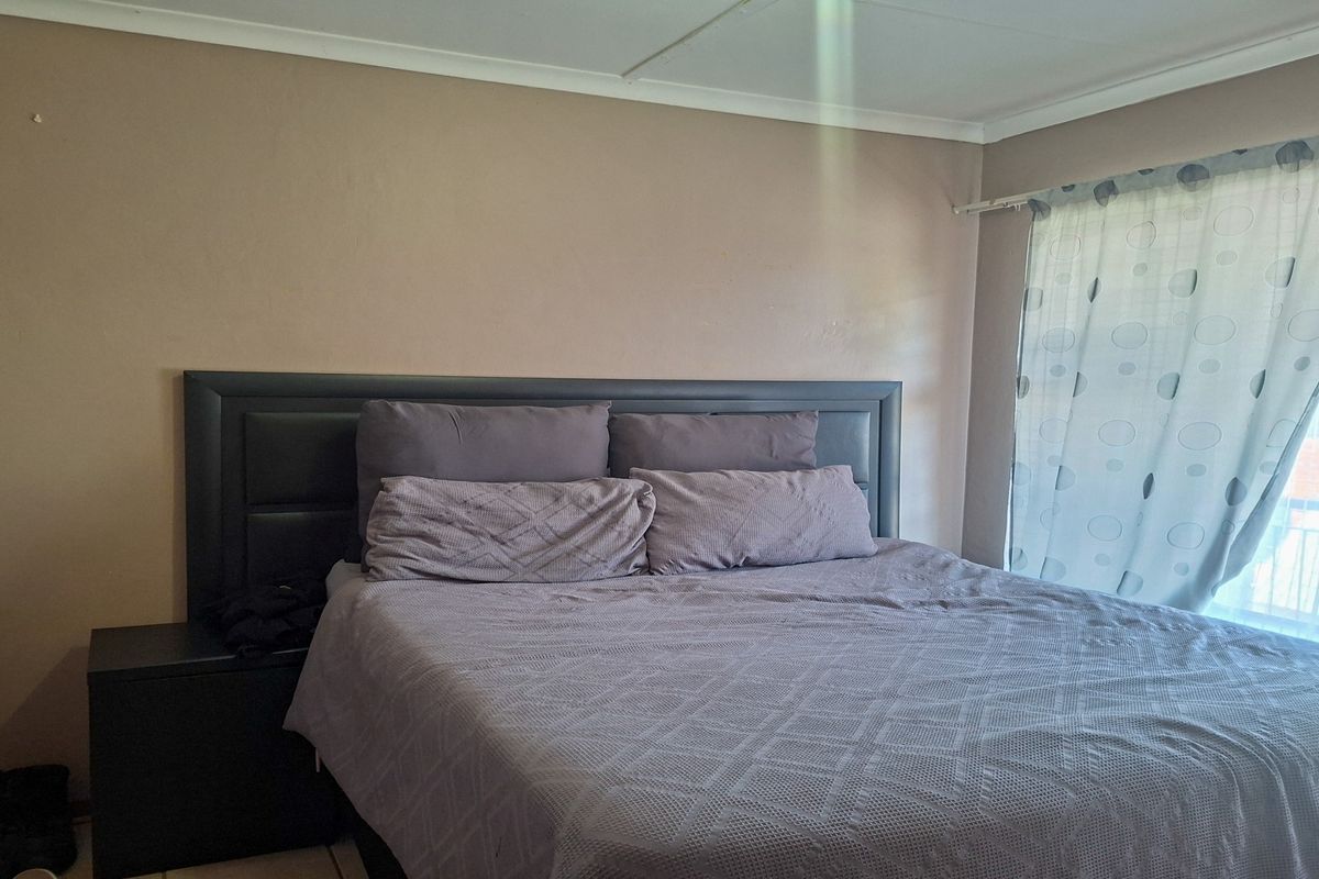 A standard bedroom featuring neutral wall finishes and a window with a fitted curtain rail.