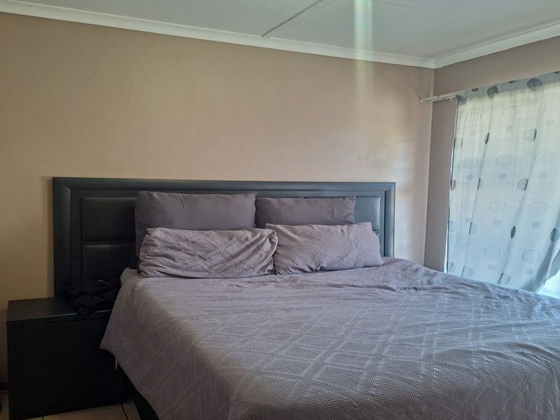 A standard bedroom featuring neutral wall finishes and a window with a fitted curtain rail.