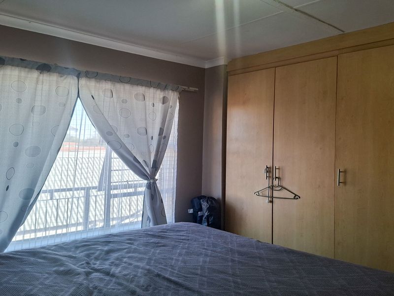A bedroom featuring built-in wooden cupboards and a window with natural light, providing functional storage space.