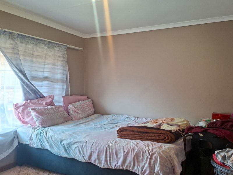 A standard bedroom featuring neutral wall paint, cove cornicing, and a window with curtain fixtures.