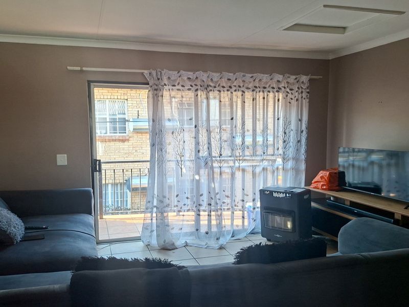 A living room featuring tiled flooring and a sliding glass door providing access to a balcony.