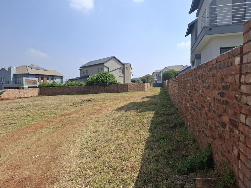A vacant residential plot featuring established brick boundary walls and surrounding residential development, offering a clear space for future construction.