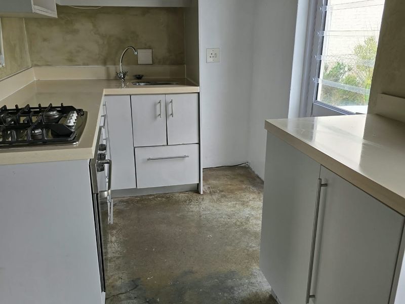 A compact kitchen featuring built-in cabinetry, a gas hob, and an extractor fan, requiring flooring and wall finish updates to improve its overall condition.