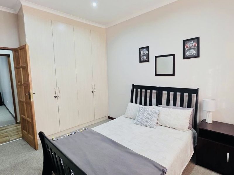 A well-maintained bedroom featuring neutral walls, carpeted flooring, and ample built-in cupboard storage space.
