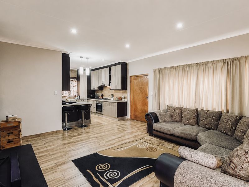 Spacious open-plan living area featuring a modern kitchen with built-in cabinetry, a central island, and tiled flooring throughout.