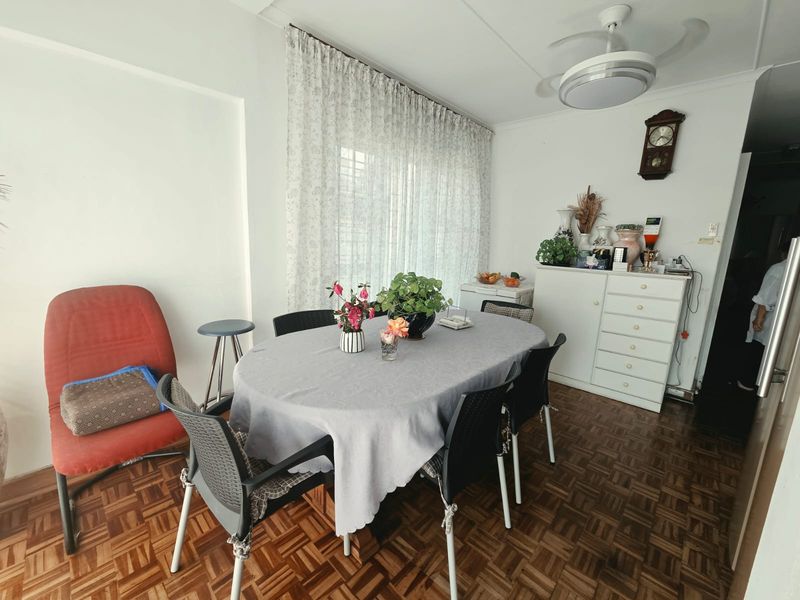 A dining room featuring classic parquet flooring and a ceiling fan, offering a functional space for family meals.