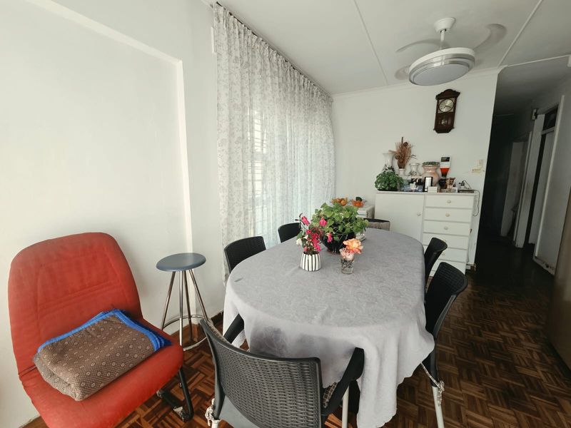 A dining room featuring classic parquet flooring and a ceiling fan, offering a functional space for family meals.