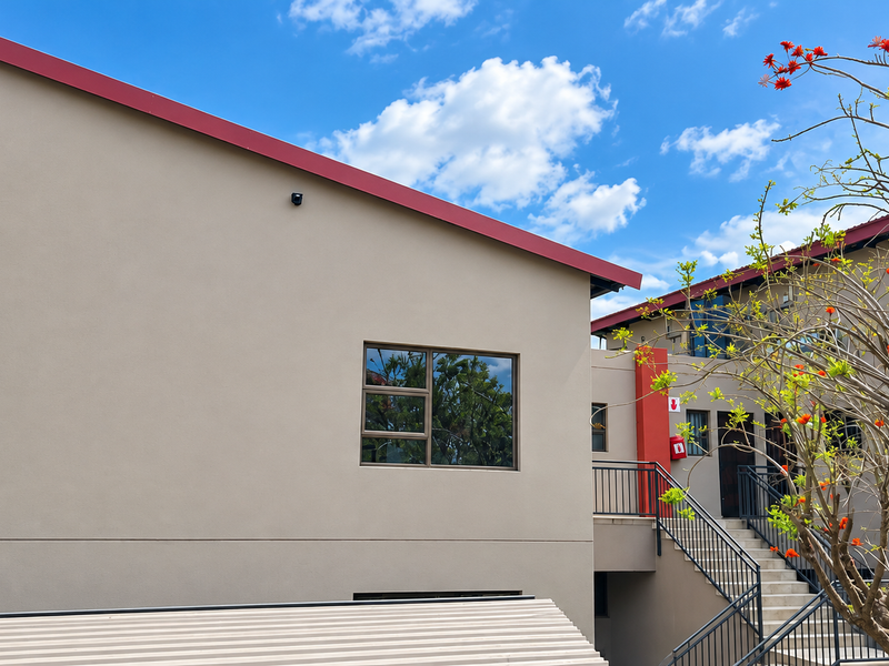 Exterior view of the apartment building featuring a modern facade, metal staircase, and clean architectural lines.