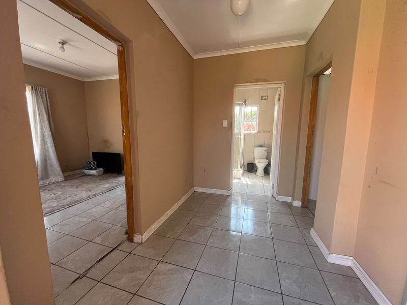 A functional hallway with tiled flooring providing access to adjacent living and bathroom areas, featuring neutral wall tones and standard architectural finishes.
