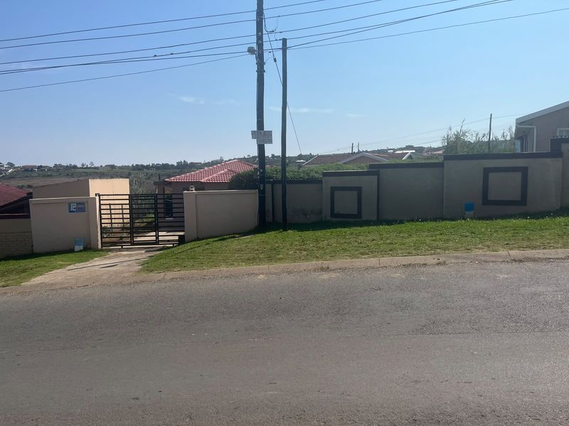 Street view of the property showing the perimeter wall, metal entrance gate, and paved driveway access.