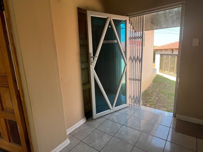Entrance area featuring tiled flooring, a security gate, and an aluminium frame door leading to the exterior.