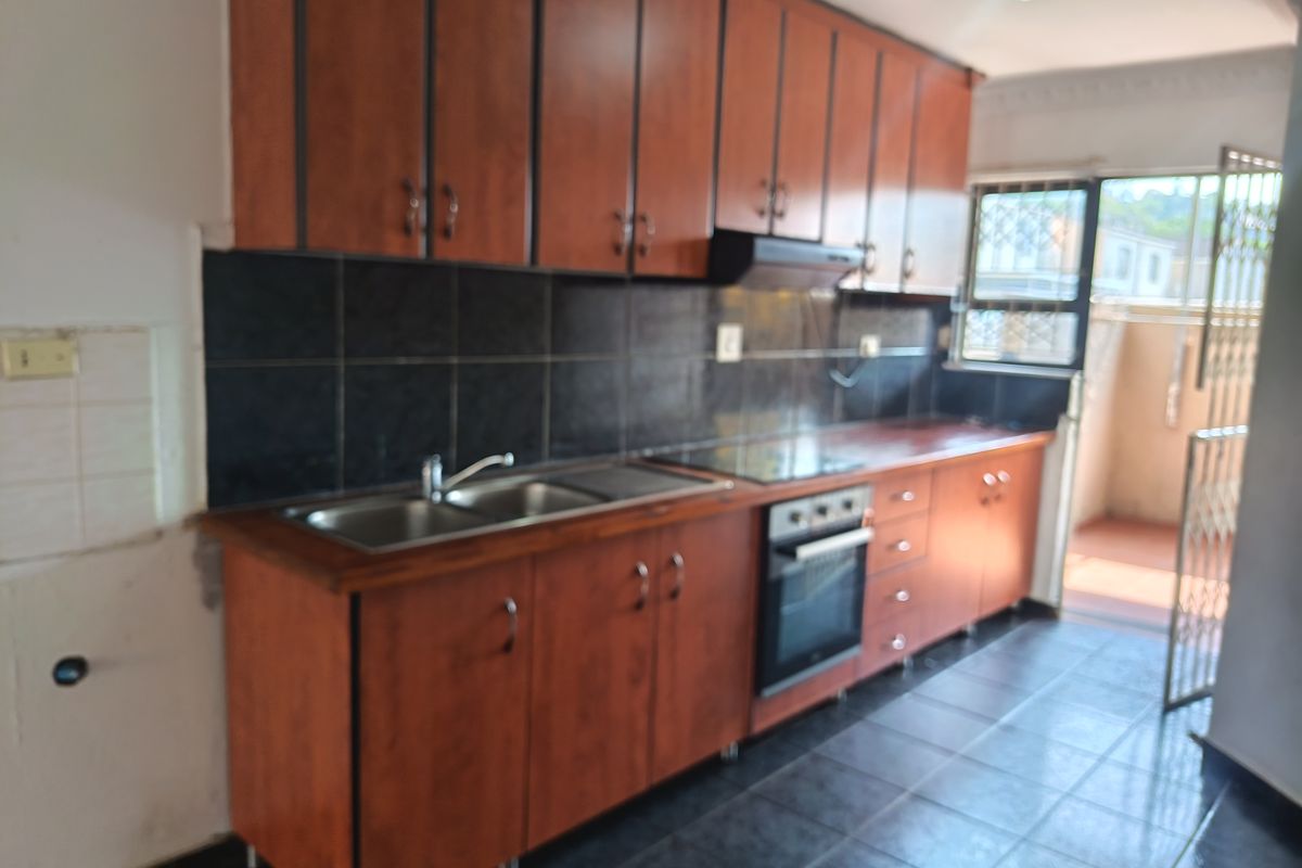 A functional kitchen featuring wooden cabinetry, a built-in oven, hob, and extractor fan, with direct access to an outdoor area.