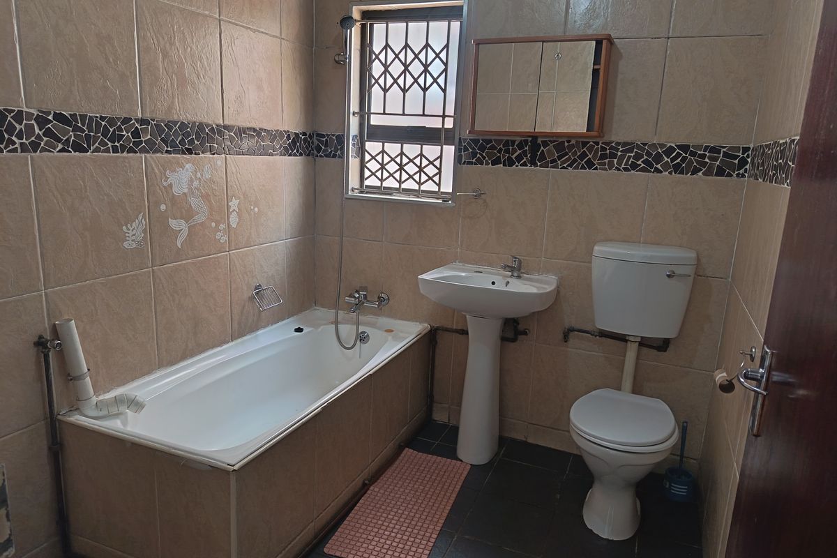 A dated bathroom featuring a bathtub, pedestal basin, and toilet with tiled walls and flooring, requiring modernization of fixtures and finishes.