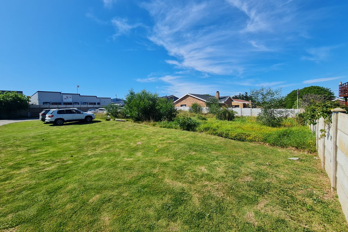 A vacant residential plot featuring a maintained lawn and precast concrete boundary walling in a suburban setting.