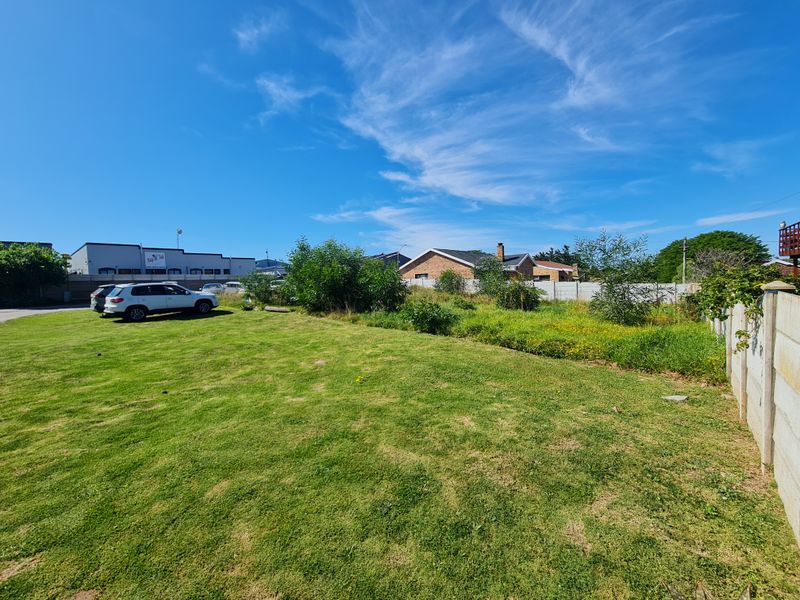 A vacant residential plot featuring a maintained lawn and precast concrete boundary walling in a suburban setting.