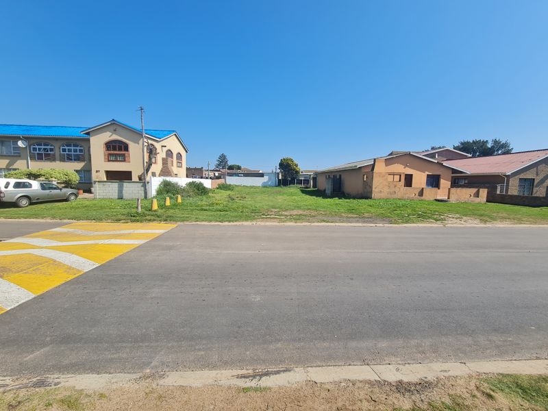 A vacant residential plot situated between existing neighboring properties, offering a clear space for potential development.