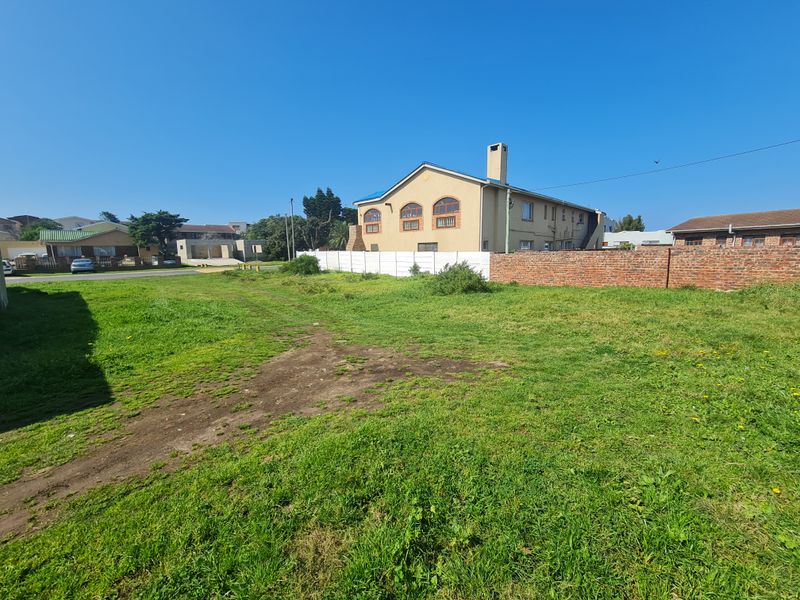 A vacant residential plot featuring grass coverage, enclosed by a combination of brick and precast concrete boundary walls.