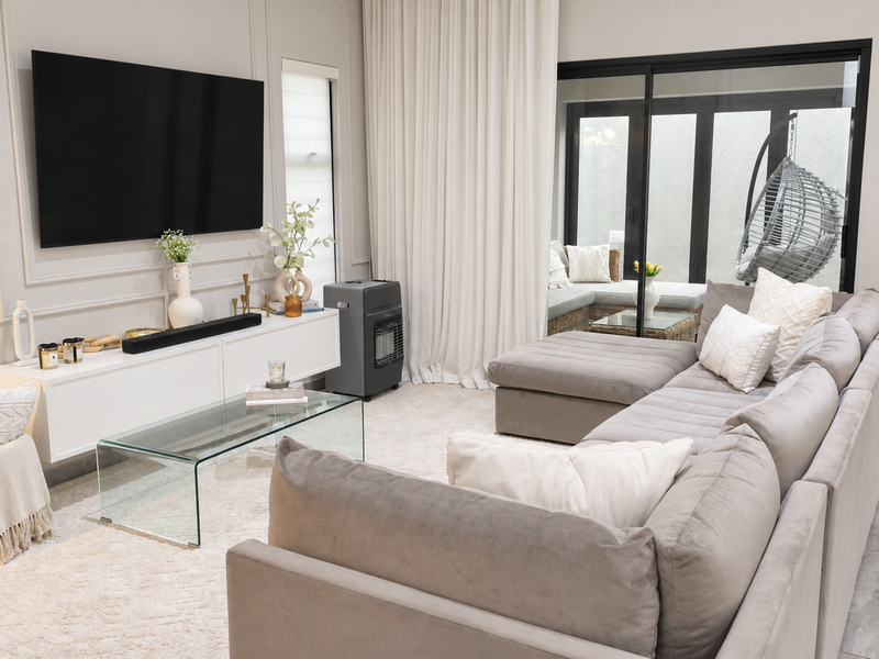 Modern living room featuring elegant wall moulding, large sliding glass doors leading to a patio, and neutral tiled flooring.