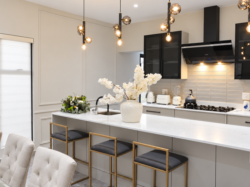 Modern kitchen featuring a large island with quartz countertops, sleek cabinetry, high-end gas cooktop, extractor fan, and elegant pendant lighting.