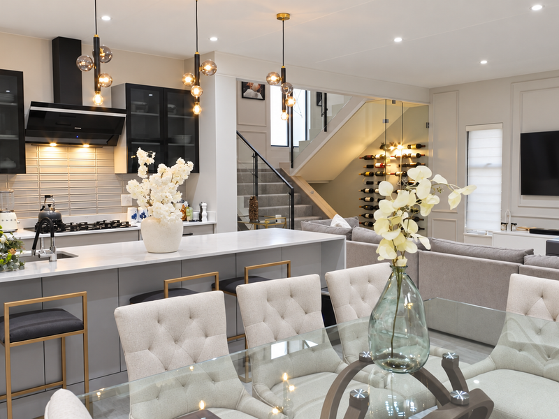 Modern open-plan living area featuring a sleek kitchen with island, integrated appliances, and a stylish staircase with glass balustrade.