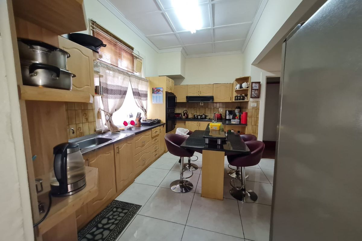 A functional kitchen featuring wooden cabinetry, tiled flooring, built-in oven, and extractor fan, offering a traditional layout with ample storage space.