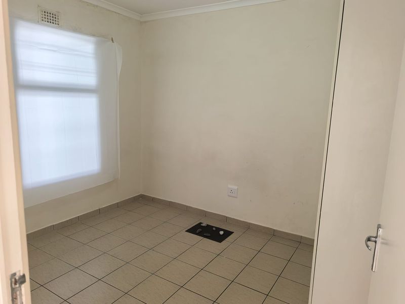 An empty bedroom featuring tiled flooring, a built-in cupboard, and neutral wall finishes, offering a blank canvas for personalization.