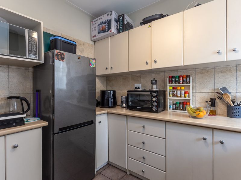 A functional kitchen featuring light-toned cabinetry, laminate countertops, and tiled backsplash, providing a practical workspace with ample storage.