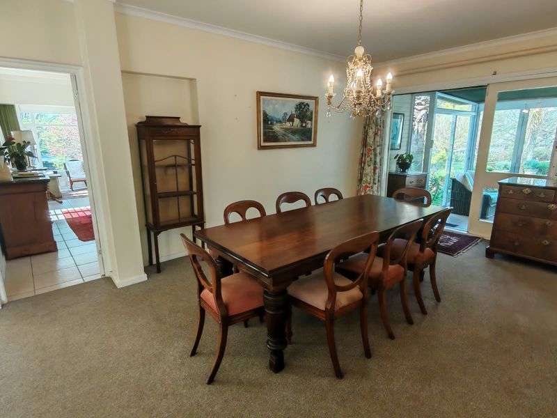 A traditional dining room featuring a crystal chandelier, carpeted flooring, and sliding glass doors providing access to an adjacent patio area.