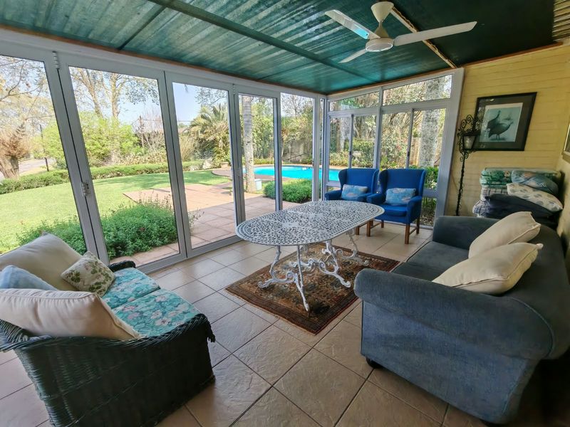 Enclosed patio area featuring tiled flooring, ceiling fan, and large sliding doors overlooking the garden and swimming pool.