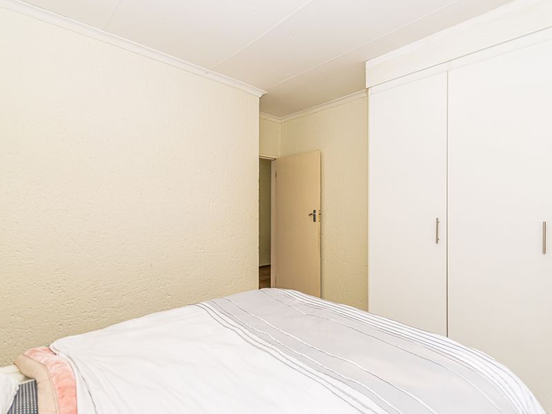 A bedroom featuring built-in white wardrobes and textured wall finishes, providing functional storage space.
