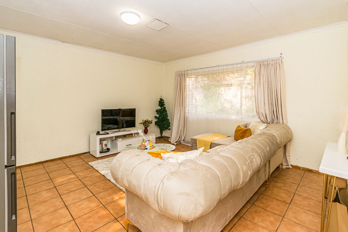A living room featuring tiled flooring and a large window, providing a functional space with potential for modern updates.