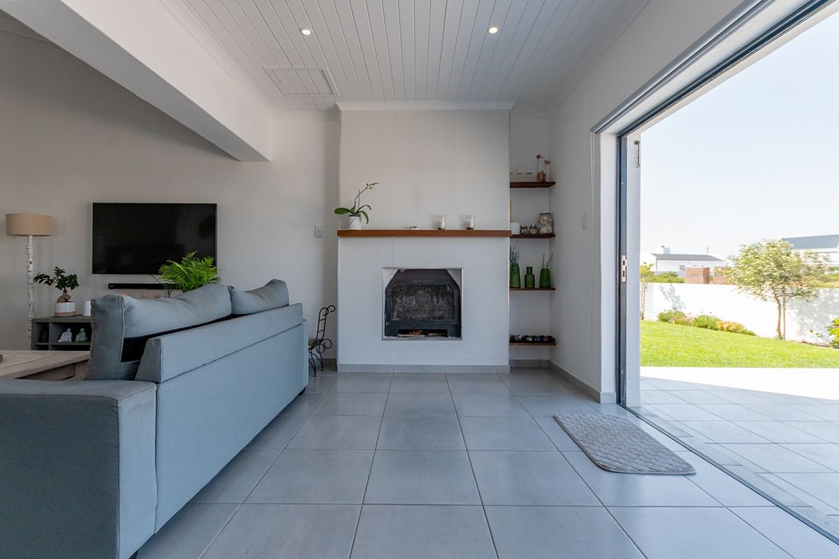 Bright living room featuring a central fireplace, built-in shelving, tiled floors, and large sliding doors opening to a rear garden patio.