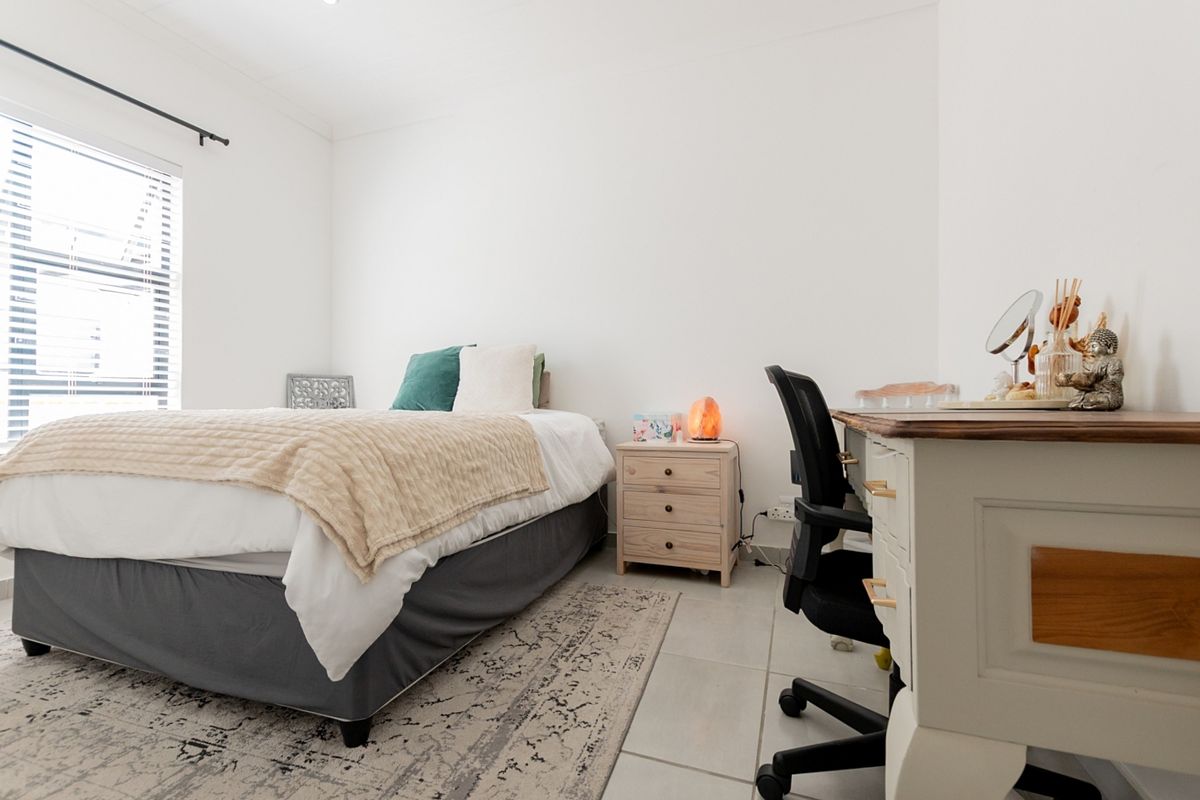 A bright and well-maintained bedroom featuring tiled flooring and a large window, providing a clean and functional living space.