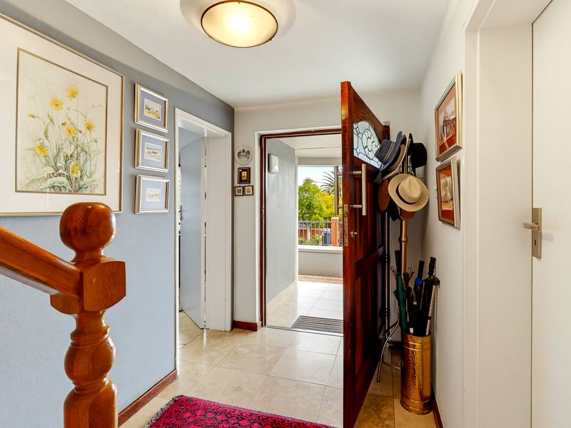 Welcoming entrance hall featuring tiled flooring, a solid timber front door, and a classic timber staircase balustrade leading to the upper level.