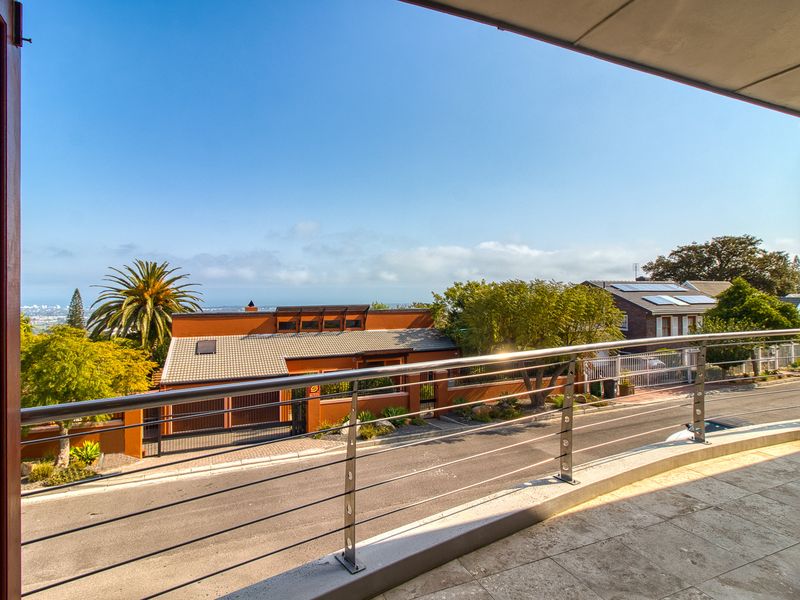 A spacious balcony featuring tiled flooring and a modern stainless steel cable railing, offering an elevated view of the surrounding neighbourhood.