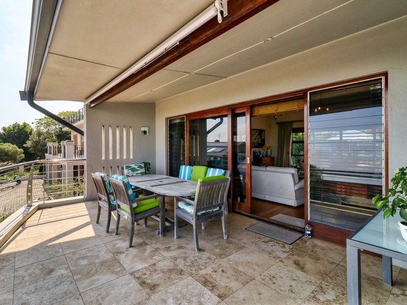 Spacious covered balcony featuring tiled flooring, stainless steel balustrades, and large sliding glass doors providing seamless access to the interior living area.