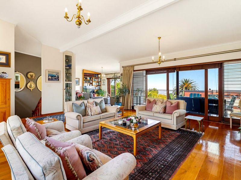 Spacious living room featuring polished hardwood floors, crown molding, and large sliding glass doors that provide abundant natural light and access to the balcony.