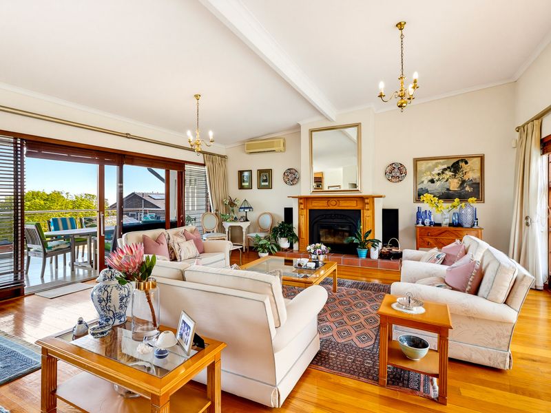 Spacious living room featuring polished wooden floors, a classic fireplace with a wooden mantel, and large sliding doors opening to an outdoor balcony.