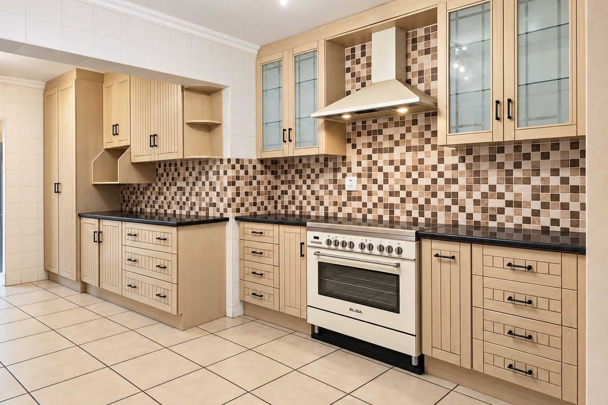 A well-maintained kitchen featuring light wood cabinetry, a tiled backsplash, granite countertops, and a built-in oven with an extractor fan.