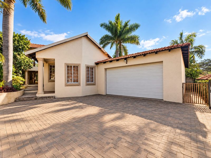 Front exterior view of the house featuring a paved driveway, a single garage, and a covered entrance with a decorative column.