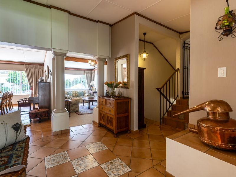 Spacious open-plan living area featuring tiled flooring, decorative columns, and a staircase leading to the upper level, creating a warm and inviting atmosphere.