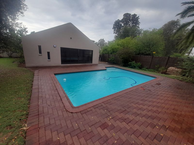 A private swimming pool area featuring brick paving, a perimeter timber fence, and direct access to the home via sliding glass doors.