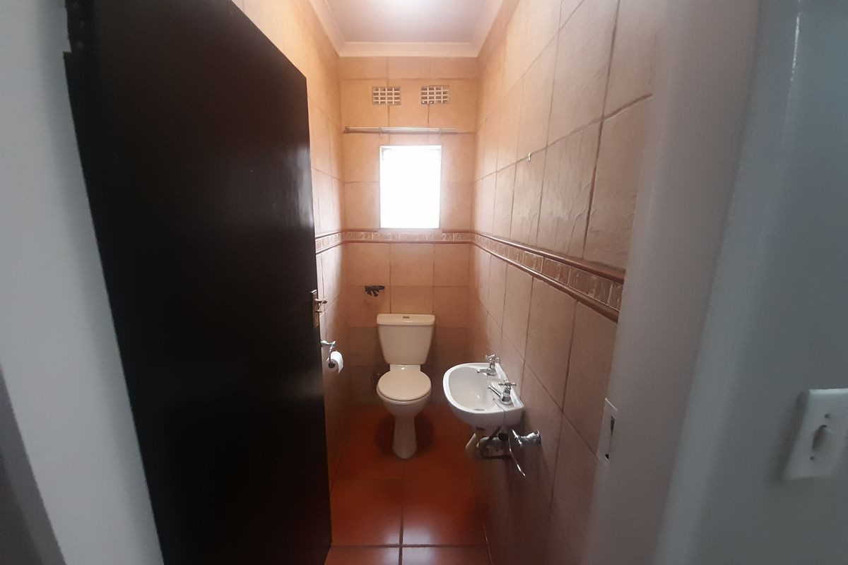 A compact guest bathroom featuring tiled walls and flooring, equipped with a standard toilet and a wall-mounted basin.